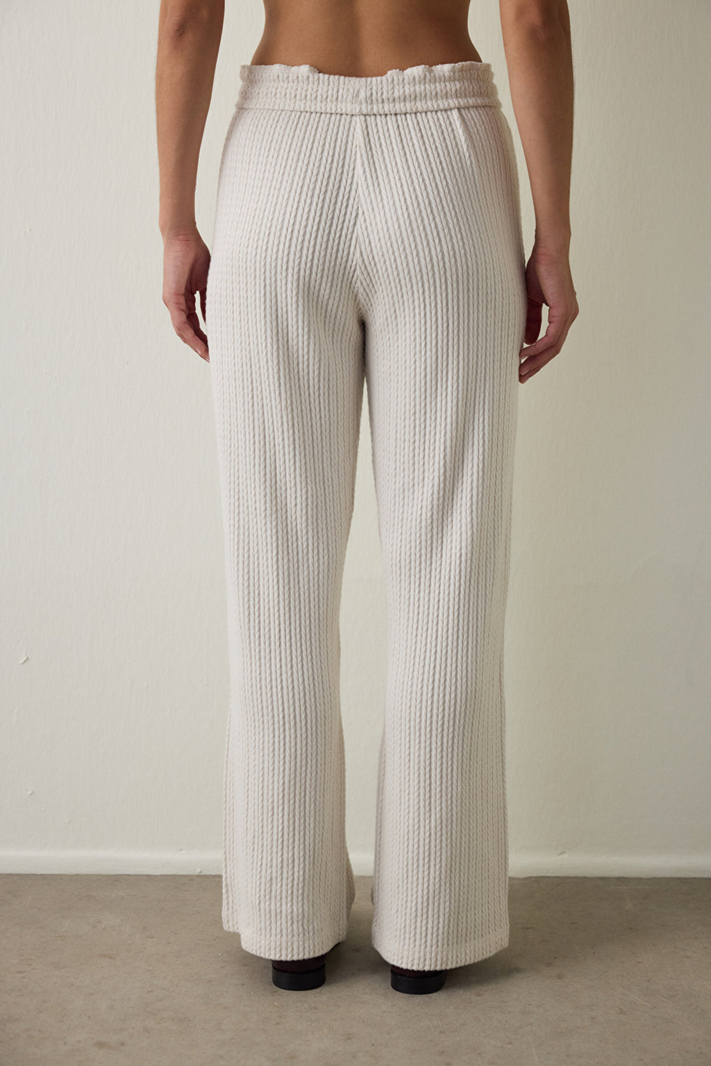 Off-white high-waisted trousers with knitted detail.